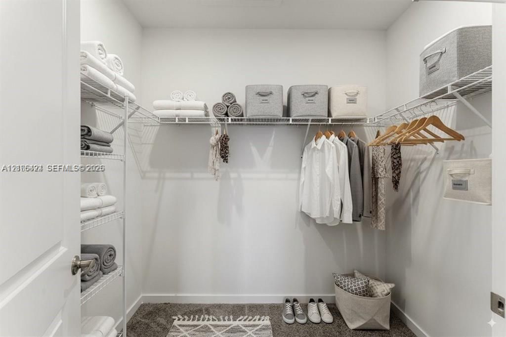 Storage area featuring white wire shelving units with multiple tiers and integrated hanging rods