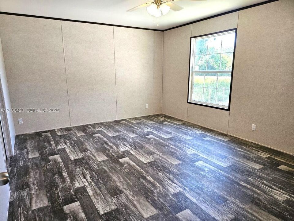 Room featuring multi-tonal wood-finish flooring, panel wall detailing, single-pane grid window, and a ceiling-mounted light fixture