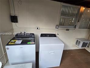 Laundry area featuring a top-load washer, a front-loading dryer, wood-finish flooring, and a wall-mounted window unit