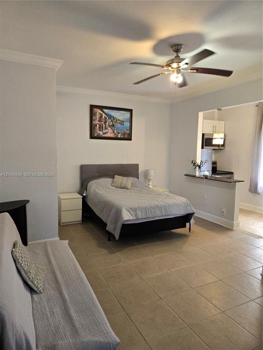 Ceramic tile flooring, crown molding, and ceiling fan with integrated lighting fixture