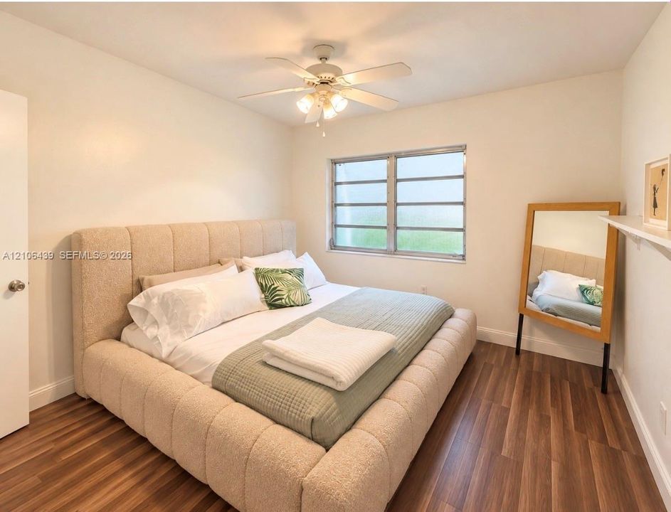Room featuring wood-finish flooring, a multi-pane horizontal sliding window, and a ceiling-mounted light fixture with a five-blade fan