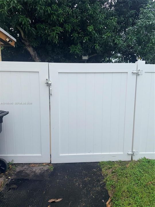 White vinyl double-gate featuring vertical paneling, metal latch hardware, and heavy-duty hinges
