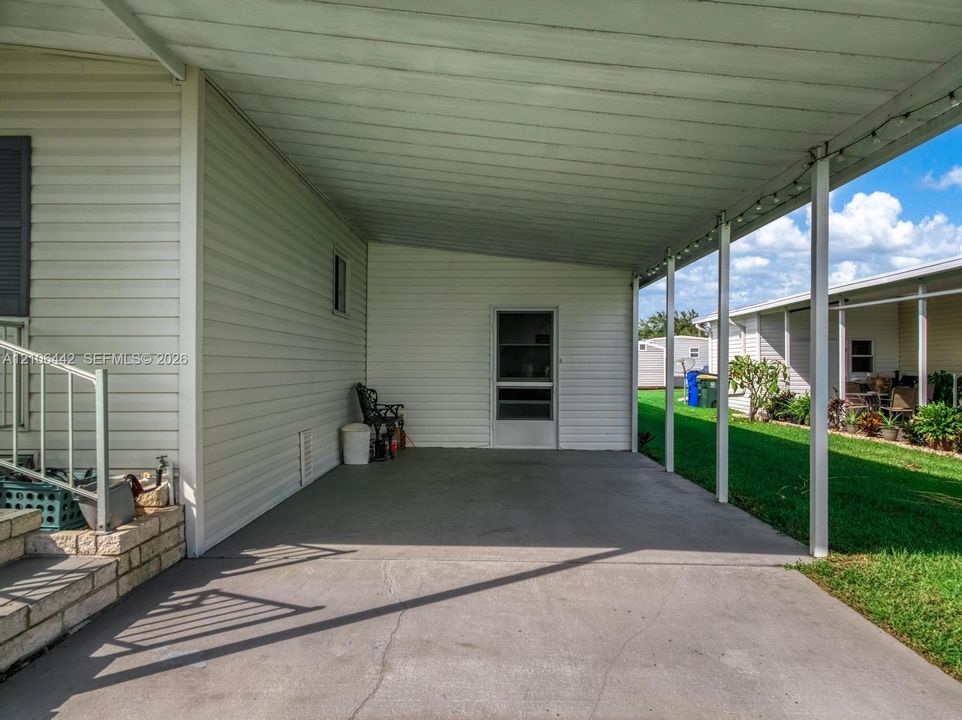Covered carport featuring a concrete surface, metal support columns, and light-colored horizontal siding