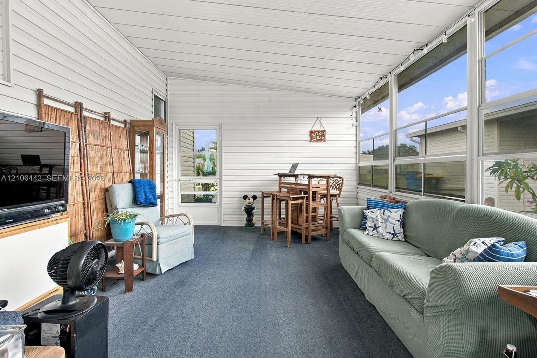 Enclosed sunroom featuring horizontal siding, large panoramic windows, and a glass-paneled entry door