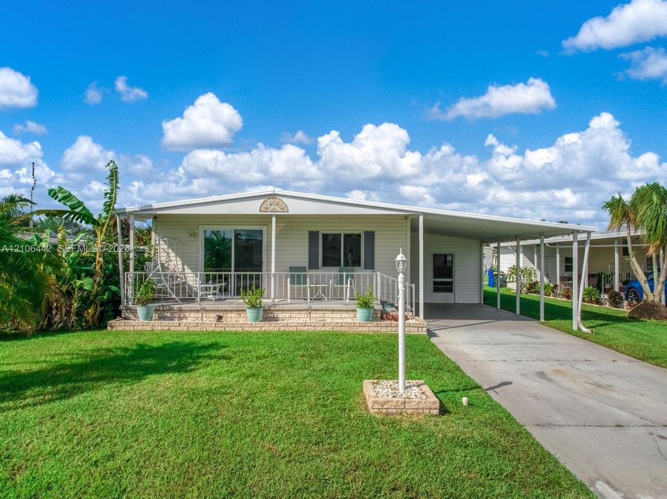 Exterior featuring horizontal siding, a raised front porch with metal railing, and an attached carport