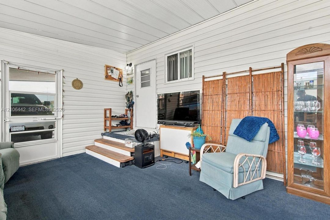 Enclosed porch featuring horizontal vinyl siding, carpeting, a multi-pane entry door, and a two-step raised landing