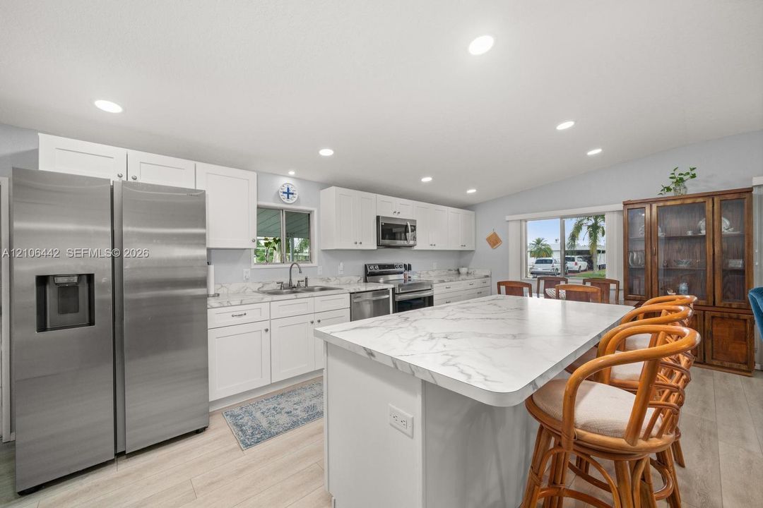 Kitchen featuring white cabinetry, stone-patterned countertops, a central island, stainless steel appliances, and recessed lighting