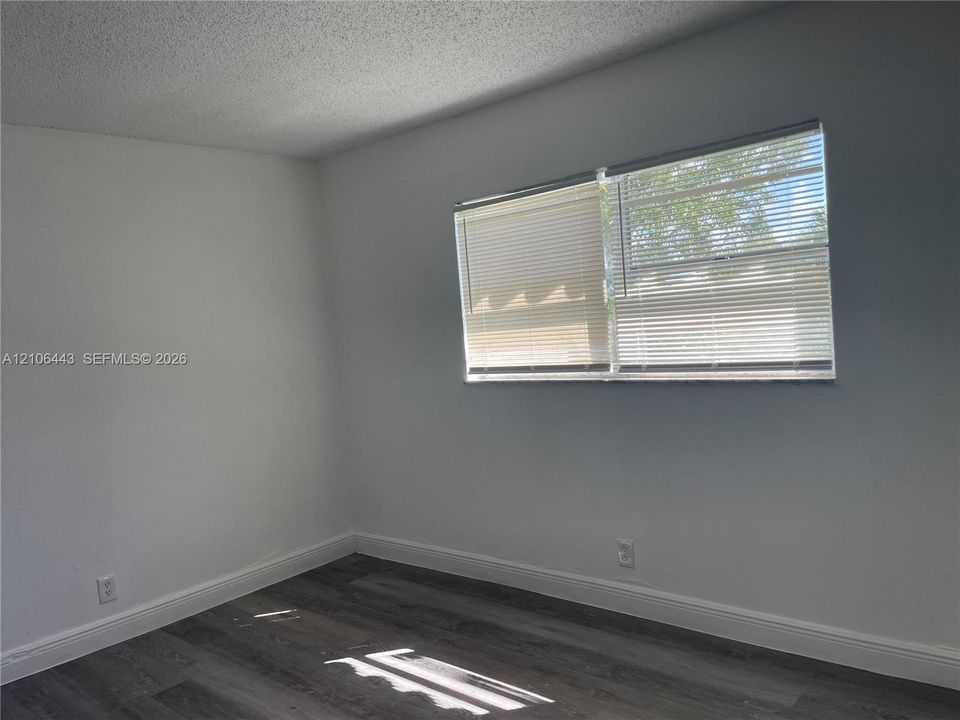 Neutral wall finishes, wood-finish flooring, and a window featuring horizontal blinds