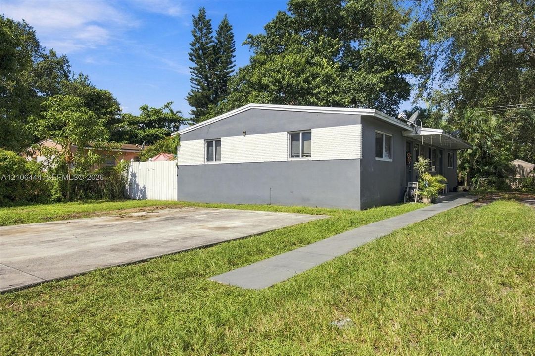 Single-story exterior featuring two-tone stucco siding, a concrete driveway, a concrete walkway, and a white privacy fence