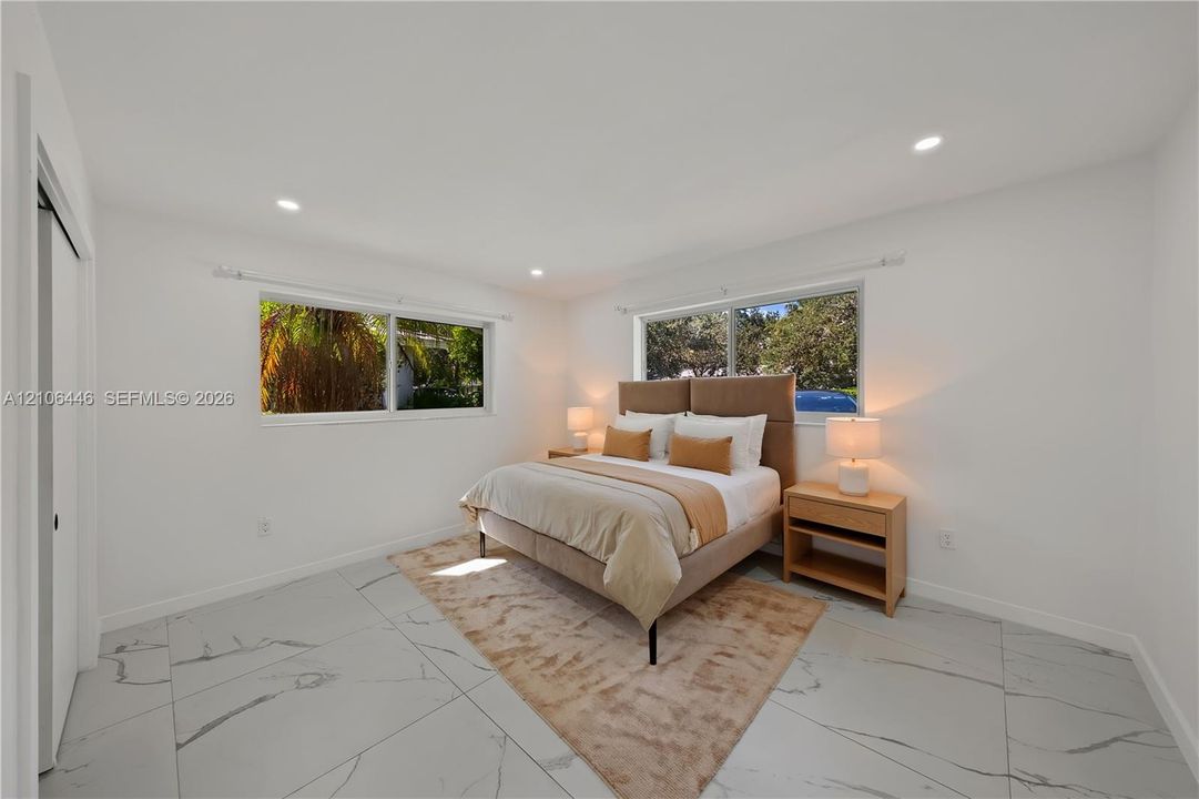 Spacious room featuring large-format porcelain tile flooring with grey veining, recessed lighting, and dual horizontal sliding windows