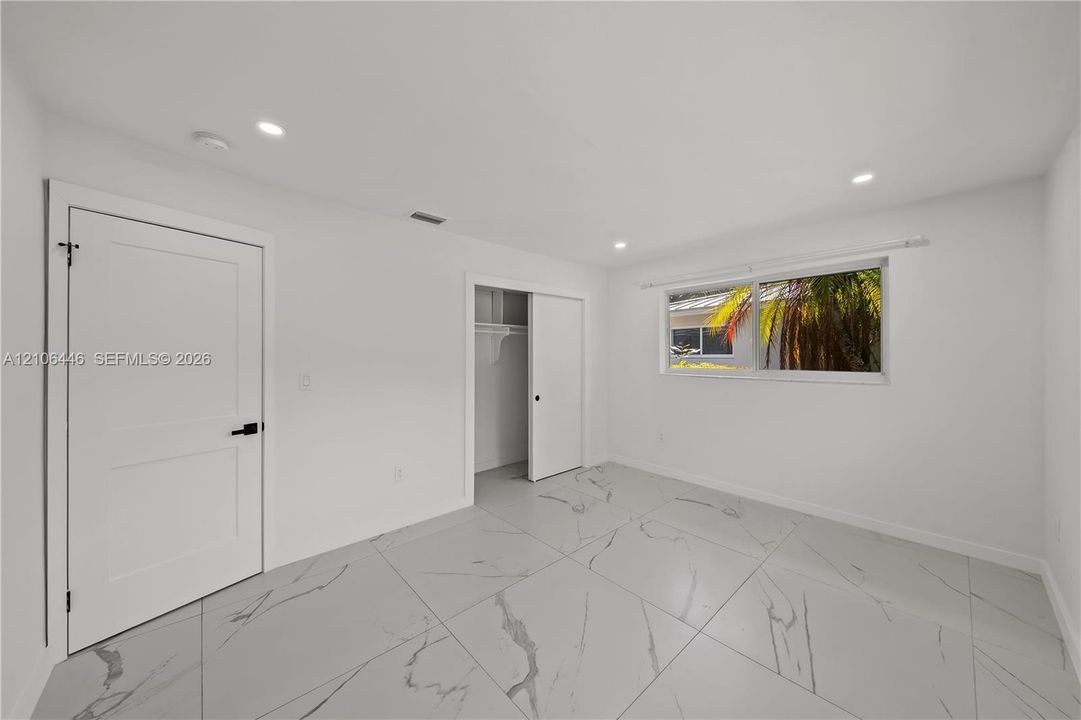 Room featuring large-format veined tile flooring, recessed lighting, and a closet with sliding doors