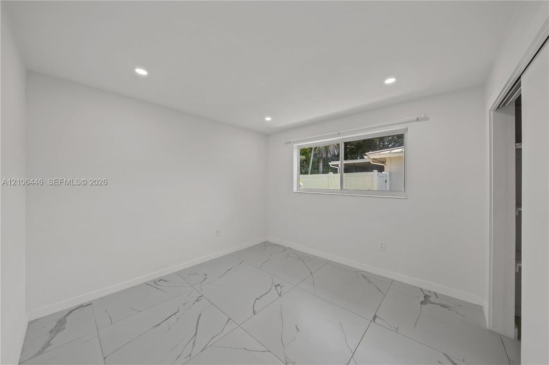 Interior space featuring large-format, stone-finish tile flooring with veining, recessed lighting, and a dual-pane sliding window