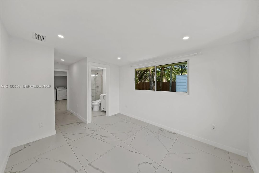 Interior space featuring large-format rectified porcelain tile flooring with a veined pattern, recessed ceiling lighting, and a window with exterior exposure