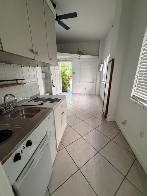 Kitchen featuring white cabinetry, square ceramic tile backsplash, integrated cooktop, stainless steel sink with a goose-neck faucet, and diagonal-set tile flooring