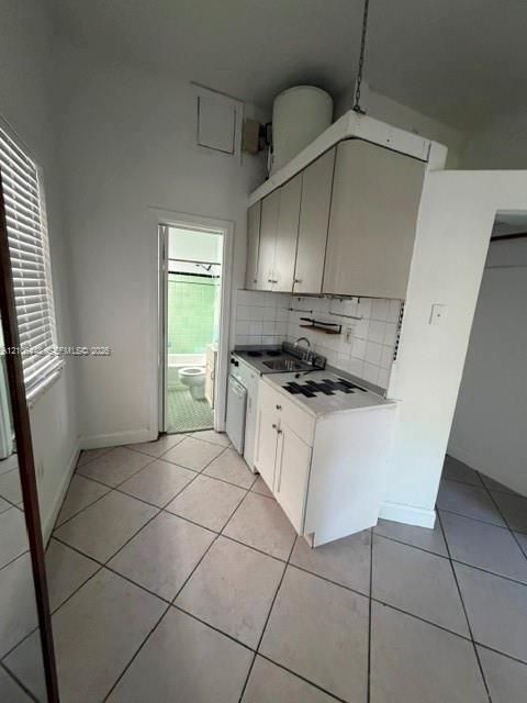 Kitchenette featuring white cabinetry, integrated sink, tile backsplash, and diamond-patterned tile flooring