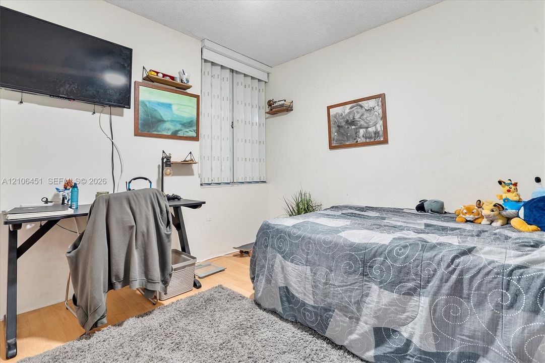 Room featuring wood-finish flooring and vertical blinds
