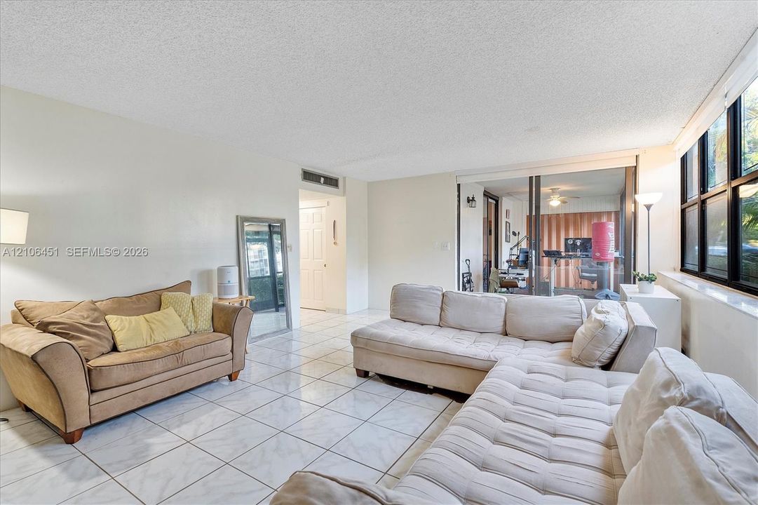 Living area featuring large format tile flooring, floor-to-ceiling windows, and sliding glass doors