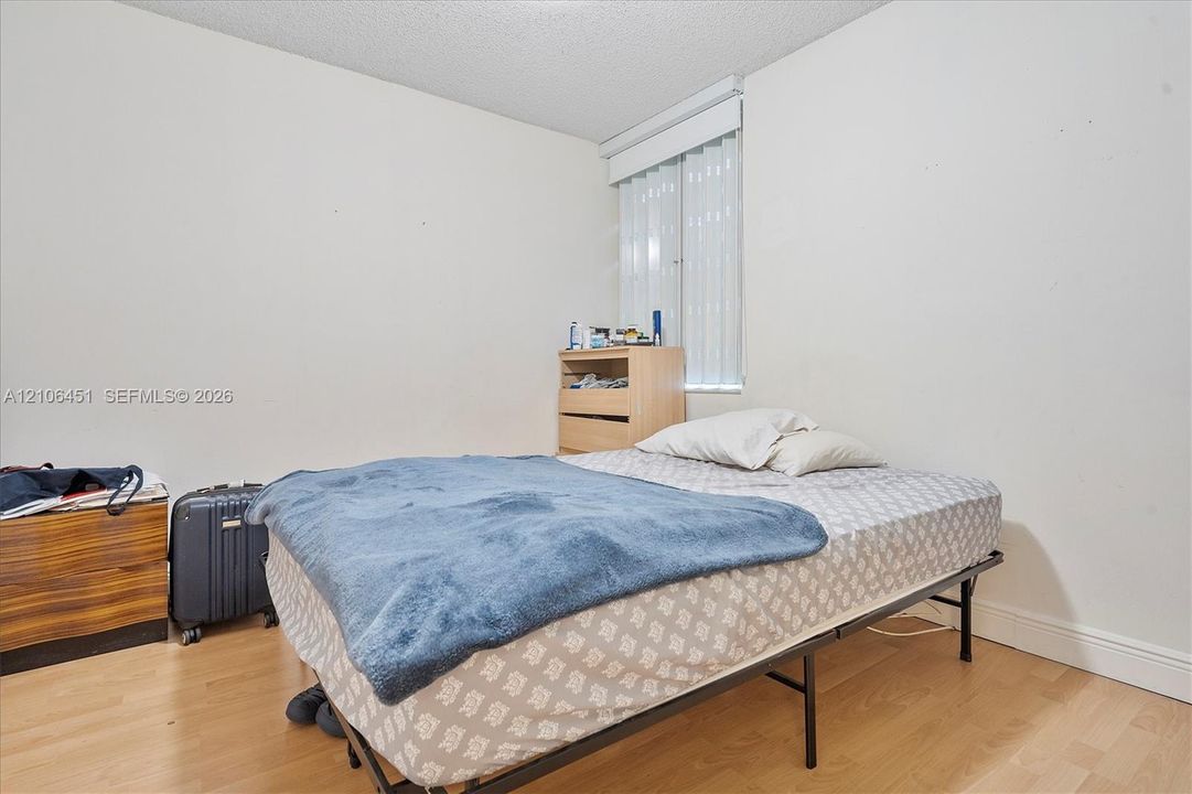 Neutral interior space featuring wood-finish flooring and a vertical blind window covering