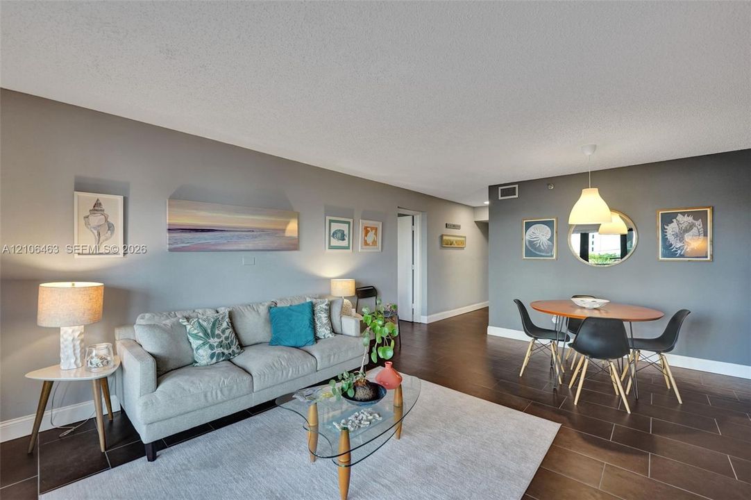 Open-concept main living area featuring dark tile flooring, dual-tone wall finishes, and suspended dome pendant lighting
