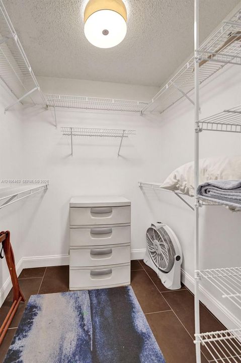 Storage area featuring white wire shelving, dark tile flooring, and a flush-mount overhead light fixture
