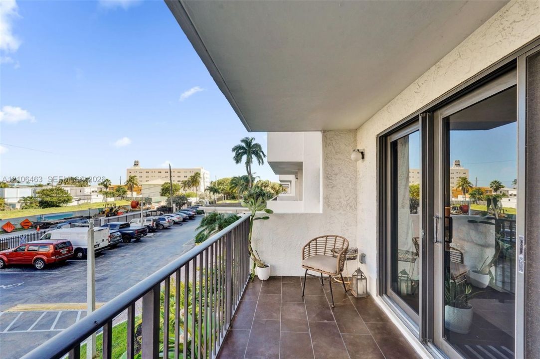 Covered balcony featuring tile flooring, metal railing, and floor-to-ceiling glass sliding doors