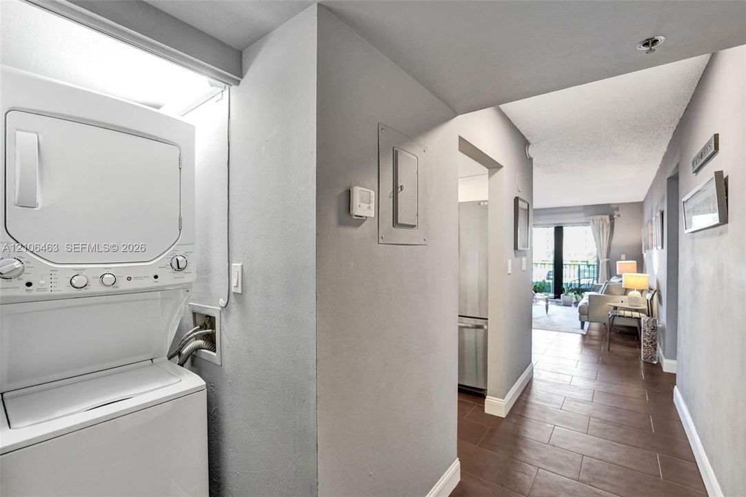 Stacked laundry unit, tile flooring, and neutral wall tones