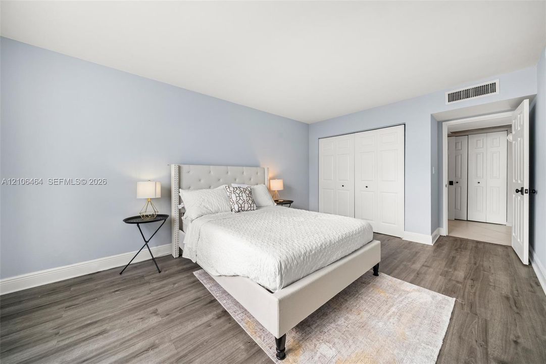 Bedroom featuring wood-finish flooring, soft-toned walls, and double-door closets