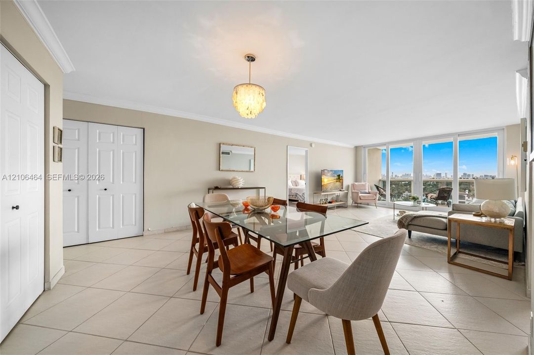 Open-concept living space featuring large-format ceramic tile flooring, floor-to-ceiling windows, and decorative drum-style chandelier lighting