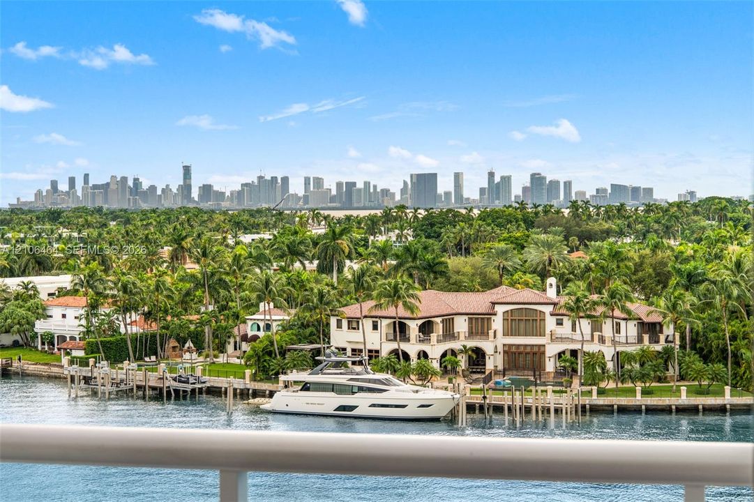 Waterfront estate featuring a private deep-water dock, multi-level arched loggias, terracotta tile roofing, and expansive skyline scenery