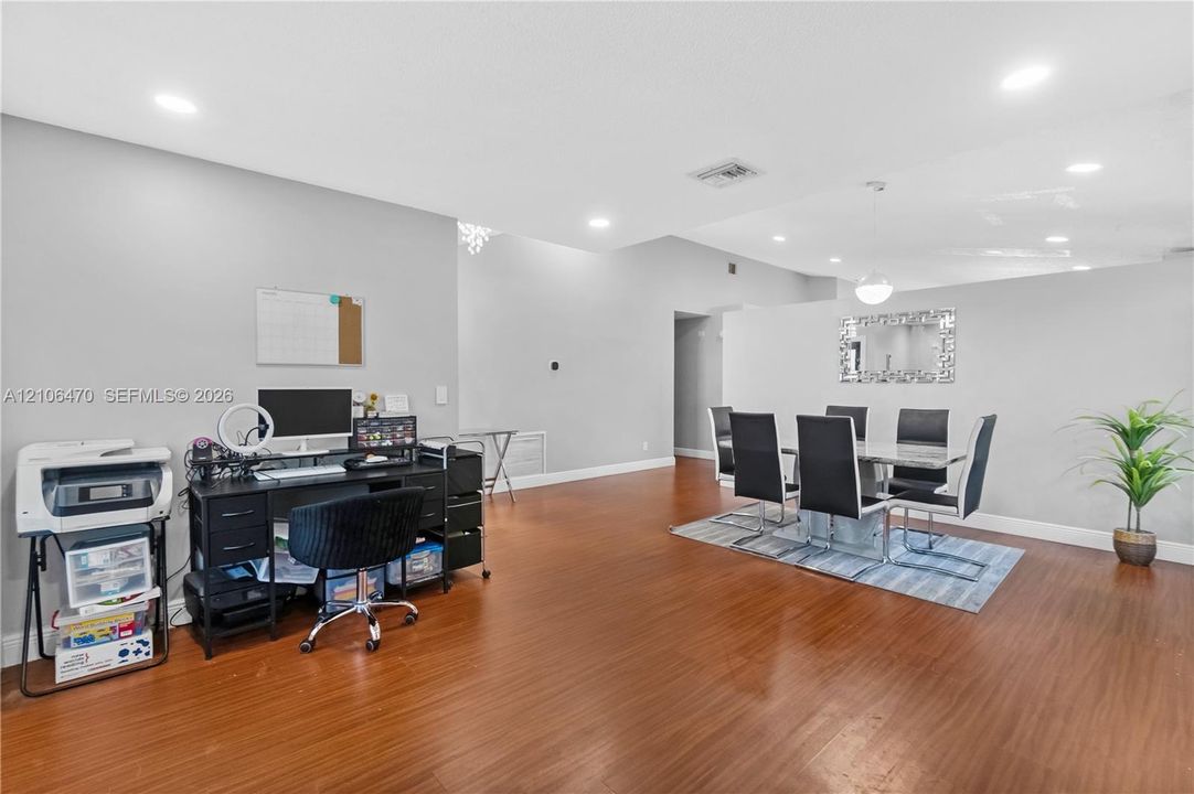 Open-concept floor plan featuring wood-finish flooring, recessed lighting, and a wall-mounted decorative mirror
