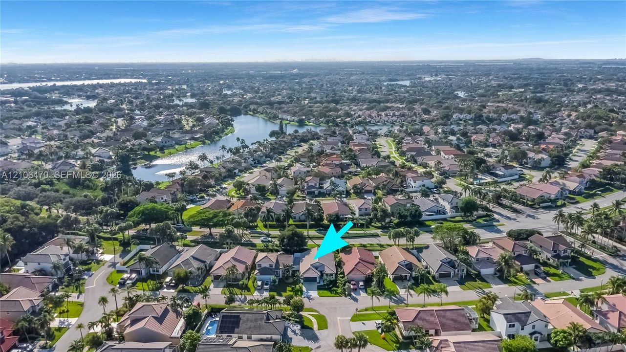 Aerial perspective featuring a single-story residence with a multi-gabled roofline and an integrated garage, situated within a master-planned community