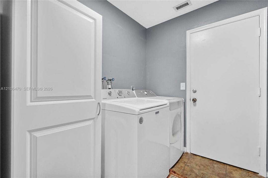Laundry room featuring built-in storage cabinetry, tiled flooring, and a dedicated service door