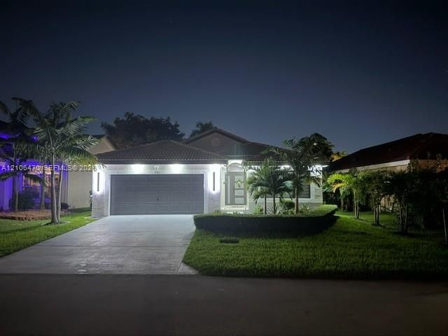 Single-story residence featuring a tile roof, concrete driveway, and attached two-car garage