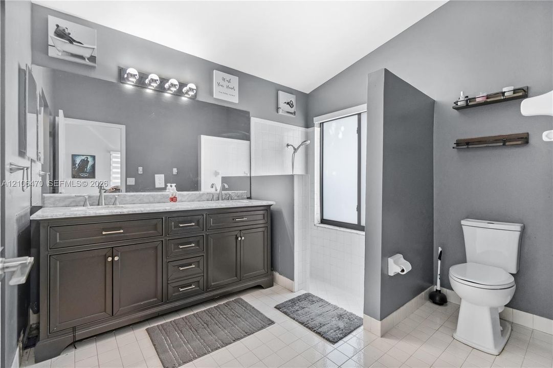 Double vanity featuring dark cabinetry, stone-finish countertops, dual under-mount sinks, and a full-width mirror