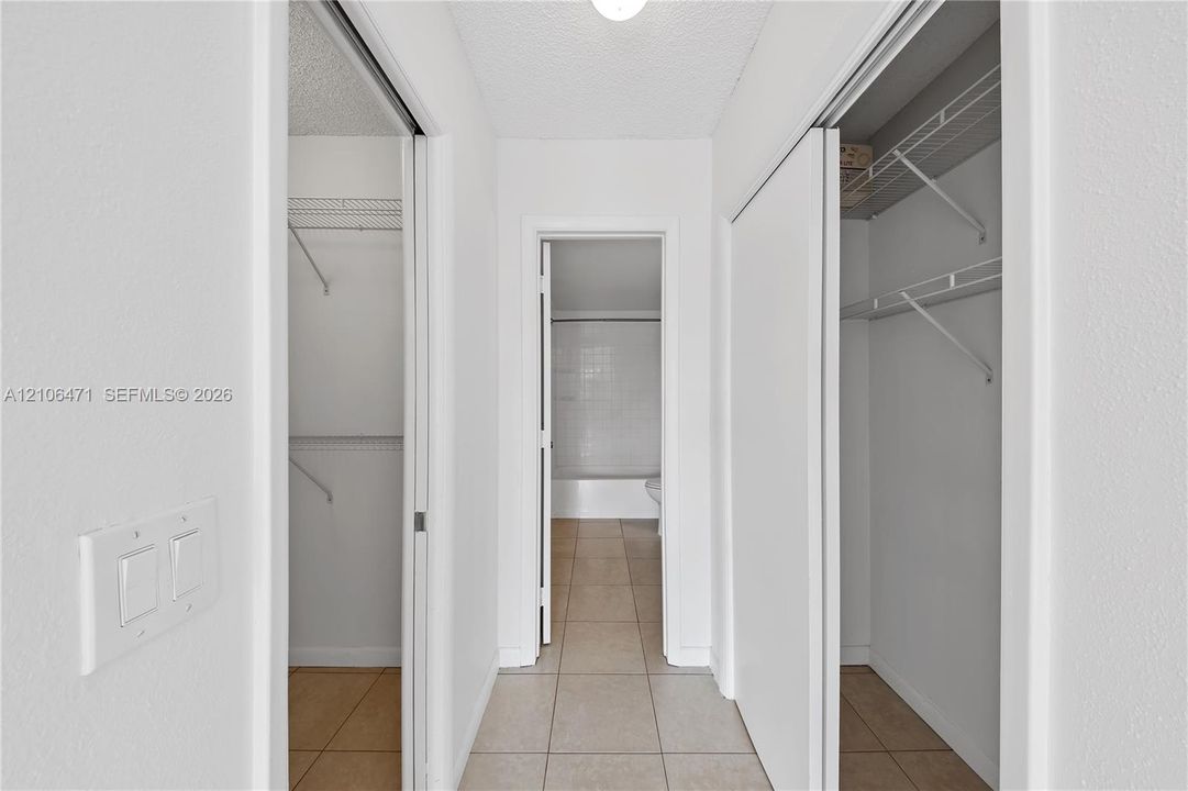 Dual reach-in closets with built-in wire shelving, tile flooring, and neutral wall finishes