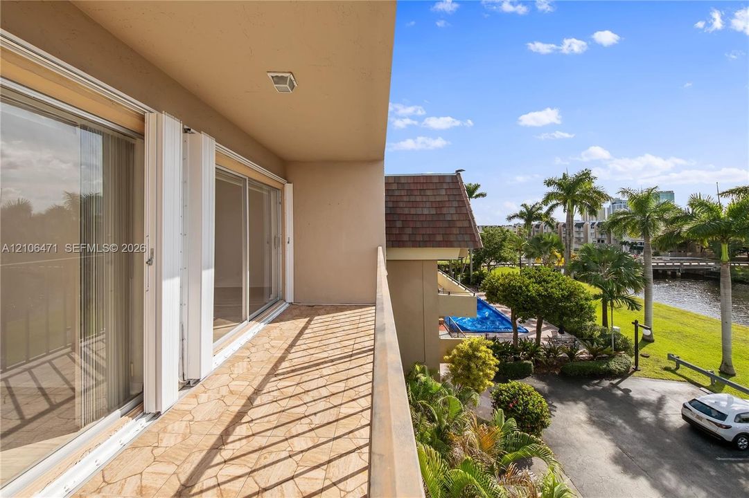 Covered balcony featuring stone-patterned tile flooring and floor-to-ceiling sliding glass doors