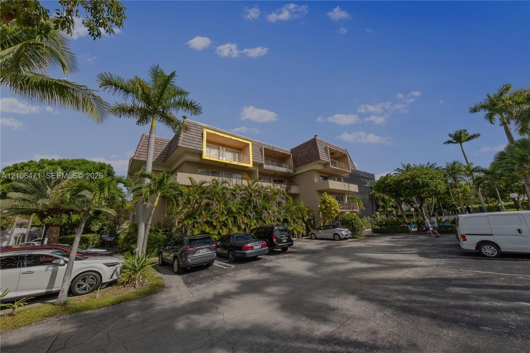 Multi-story residential building featuring a brown tile roof, stucco exterior, and private balconies