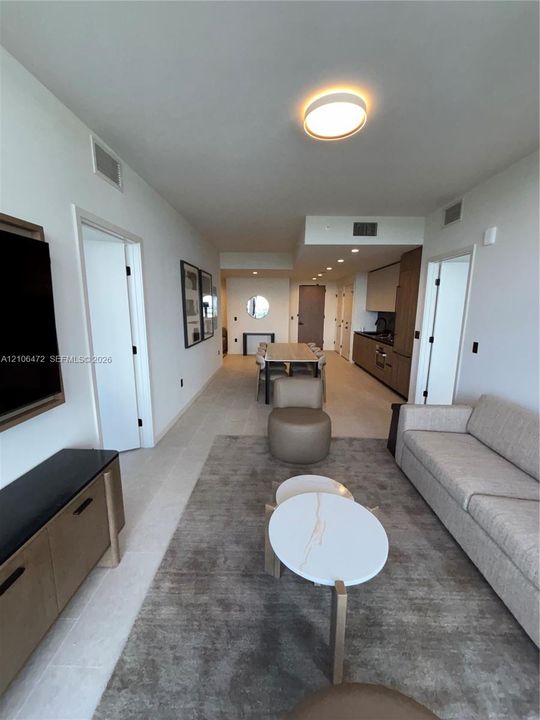 Open-concept interior featuring light-toned flooring, recessed ceiling lighting, flush-mount lighting, and custom cabinetry with integrated kitchen appliances