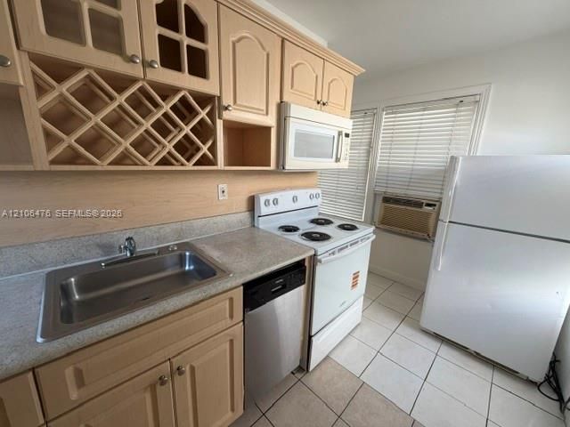 Kitchen featuring light-finish wood cabinetry, integrated wine storage, laminate countertops, a stainless steel sink, and ceramic tile flooring