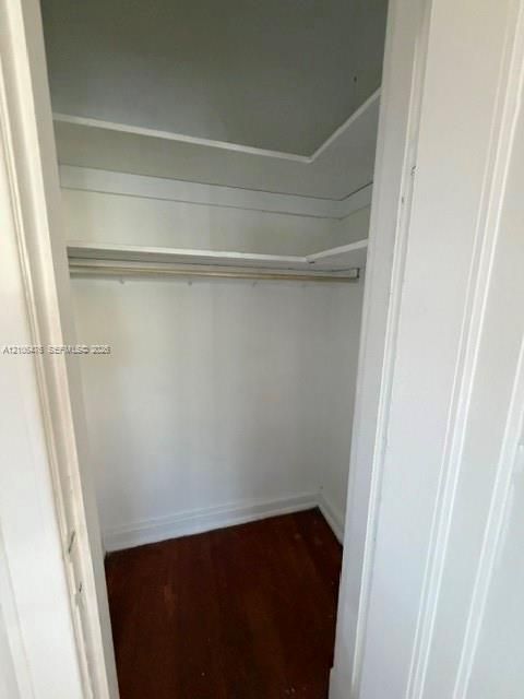 Storage area featuring wood-finish flooring, two tiers of built-in shelving, and a garment rod