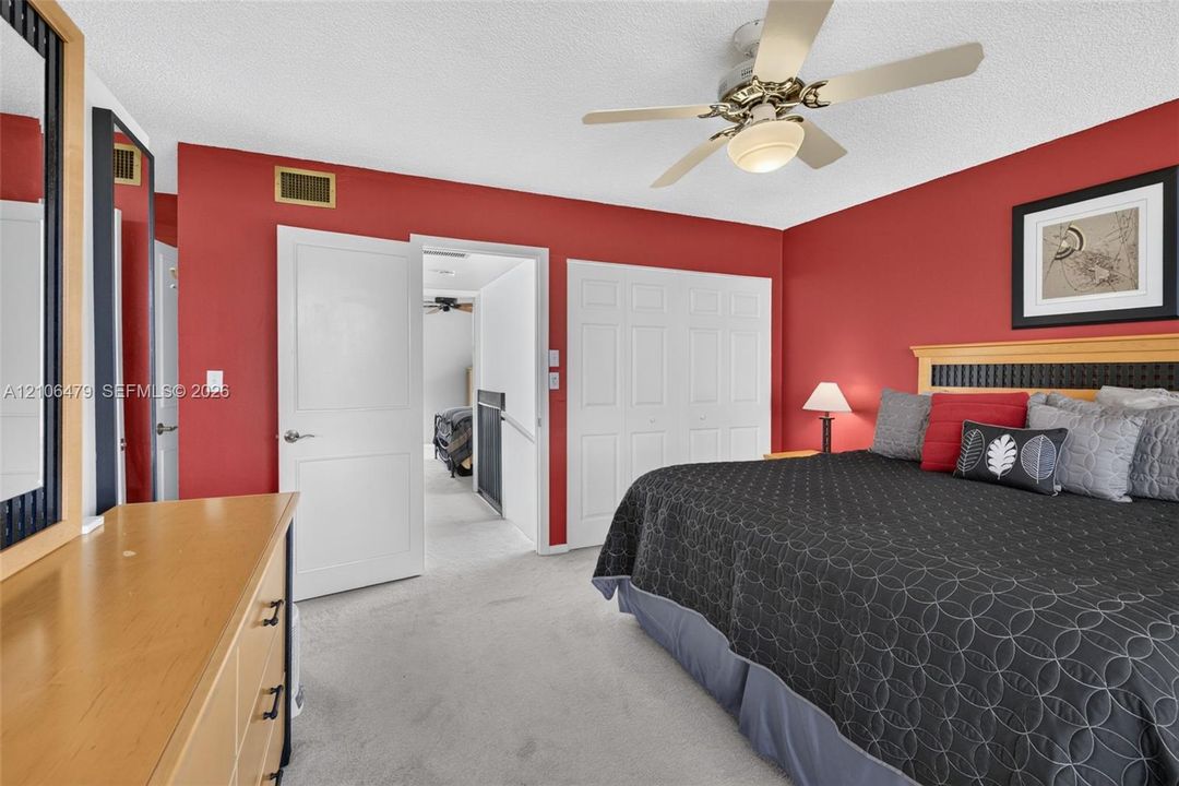 Room featuring neutral carpeting, multi-panel closet doors, and a ceiling fan with integrated lighting