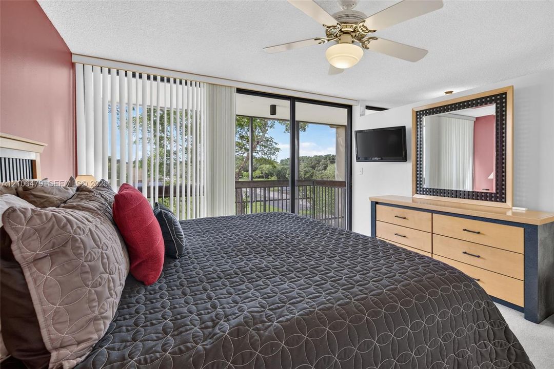 Sliding glass doors with vertical blinds, ceiling fan with light fixture, and outdoor balcony access