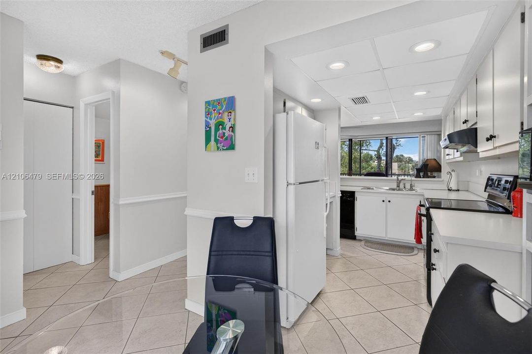 Kitchen featuring white cabinetry, integrated appliances, recessed lighting, and tile flooring
