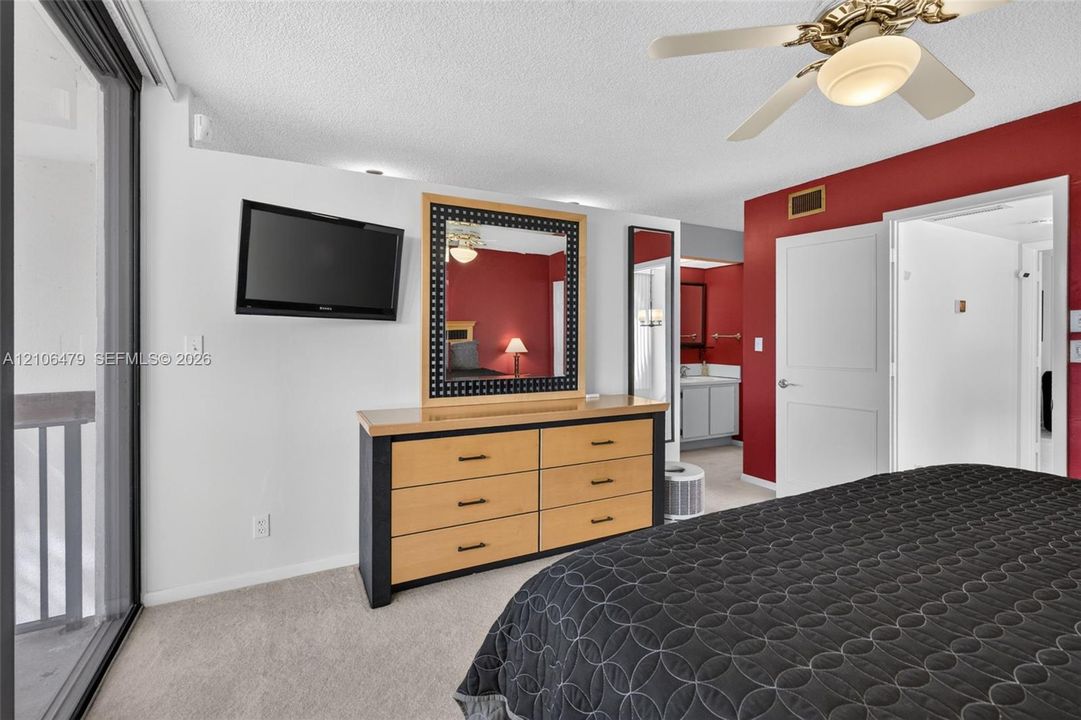 Wall-to-wall carpeting, ceiling fan with integrated lighting, glass sliding door, and neutral wall tones
