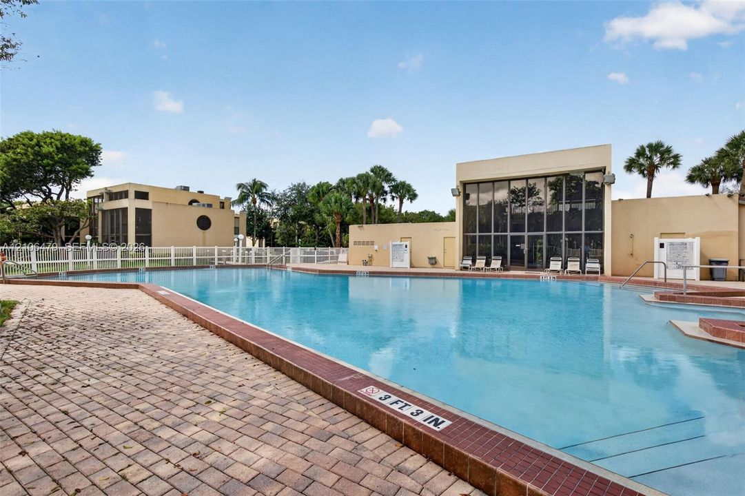 Swimming pool featuring a concrete deck, tile coping, integrated steps, and a perimeter safety fence