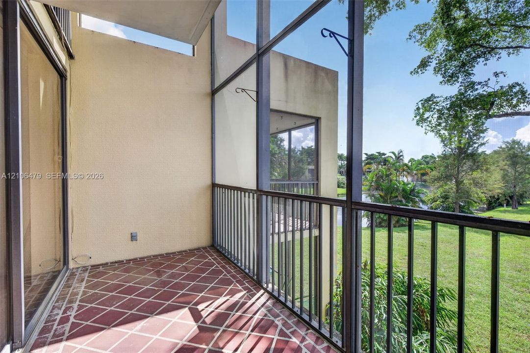 Screened balcony featuring tiled flooring, metal railings, and a solid wall exterior