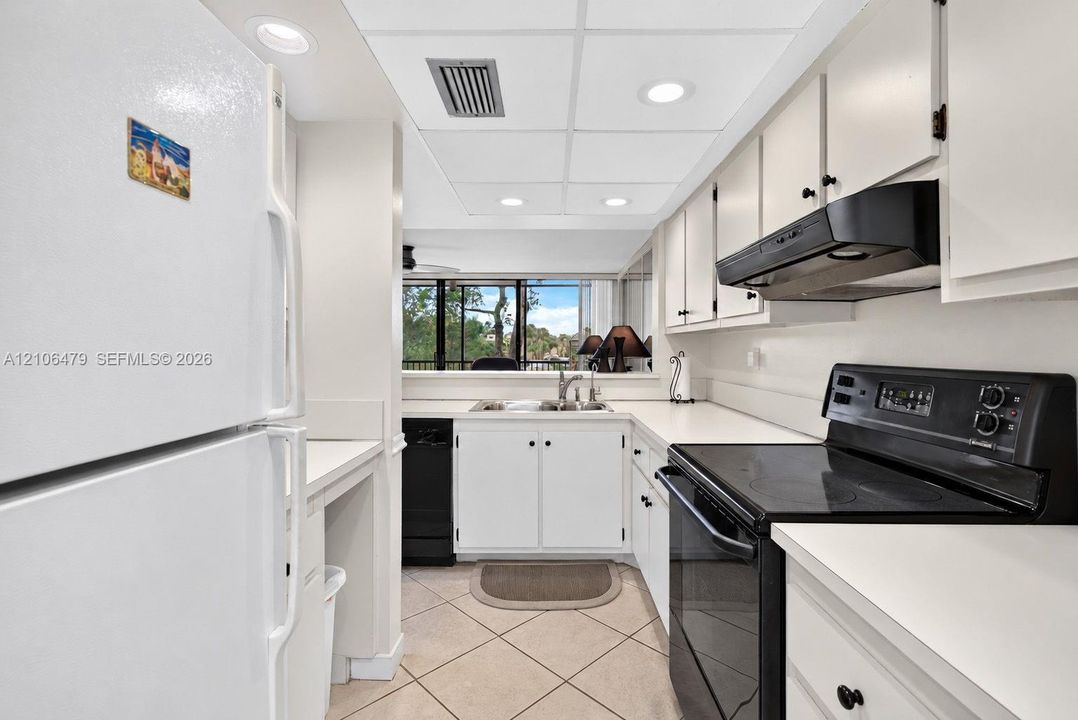 Kitchen featuring white cabinetry, contrasting black appliances, recessed lighting, and tile flooring