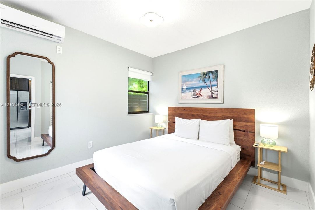 Wall-mounted ductless air conditioning unit, polished tile flooring, and single-pane window with roller shade