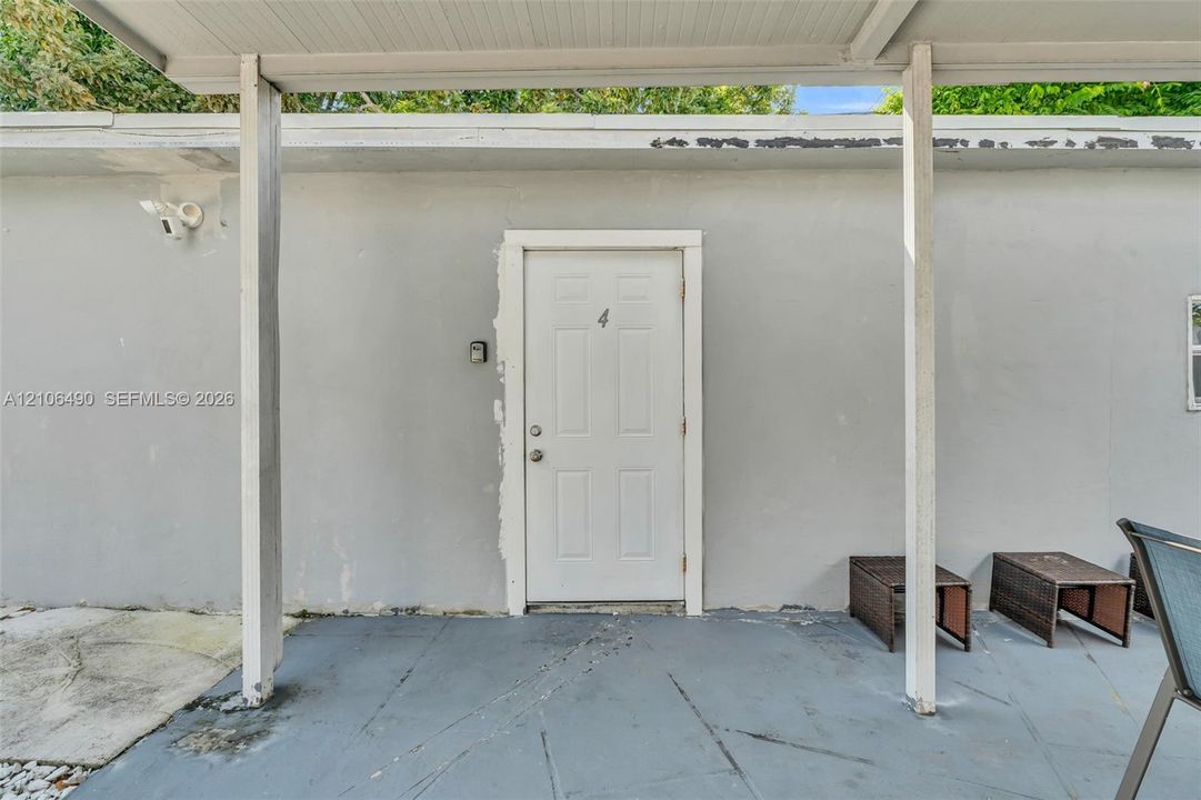Covered exterior entry featuring a painted concrete patio, a paneled door, and structural support posts