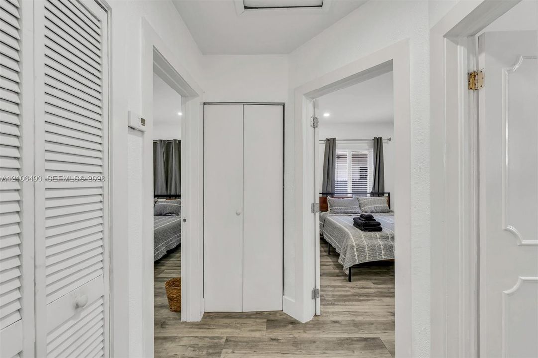 Hallway featuring wood-finish flooring, white louvered closet doors, and recessed lighting